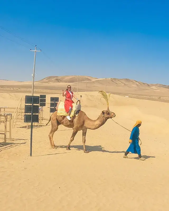 Turista realizando paseo en dromedario en el desierto durante el Full Day Dromedarius y Huacachina Ica desde Lima