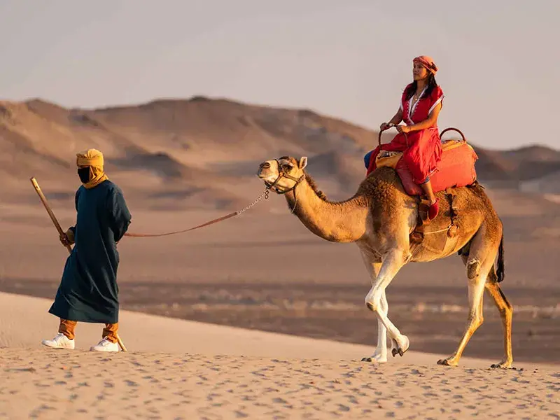 Turista realizando paseo en dromedario durante el Full Day Dromedarius y Huacachina Ica desde Lima