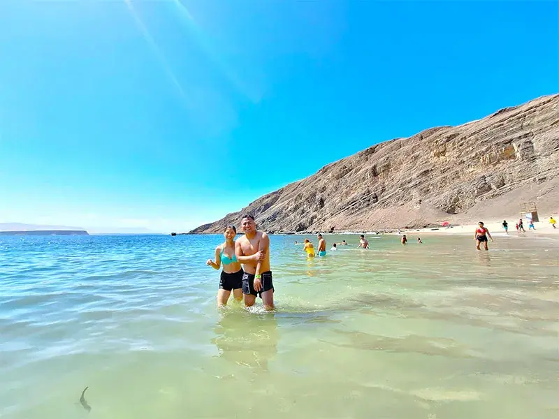 Pareja disfrutando del mar en Playa La Mina durante el tour Full Day Paracas Islas Ballestas y Playa La Mina desde Lima