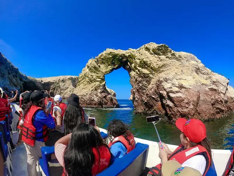 Turistas observando el arco natural de las Islas Ballestas durante el Tour 2 dias Paracas Ica con Hotel en Paracas desde Lima