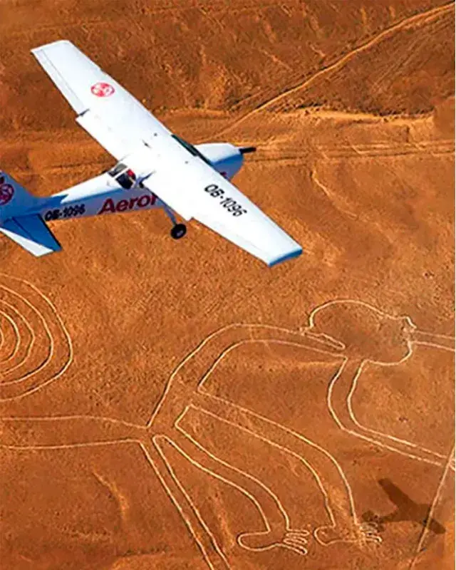 Primer plano de una avioneta durante un sobrevuelo Líneas de Nazca, pasando sobre la figura del Colibrí en el vasto desierto peruano con montañas al fondo.