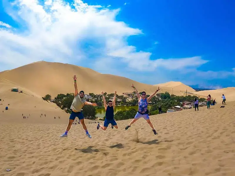 Turistas saltando en las dunas de Huacachina durante el Tour Paracas Ica Nazca Fiestas Patrias 3 dias y 2 noches